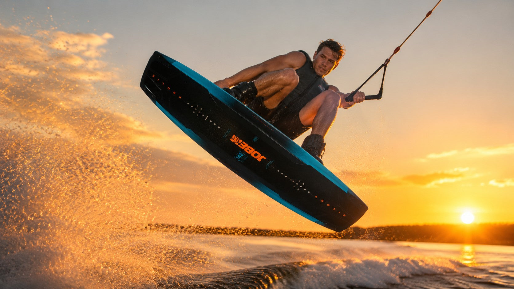 Tekne arkasında gün batımında wakeboard yapan profesyonel sporcu