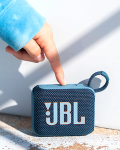 JBL Go 4 Taşınabilir Bluetooth Hoparlör mavi, üst tuşlarına basan bir el ve dokulu ızgara.