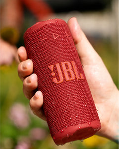 JBL Grip Taşınabilir Bluetooth Hoparlör Kırmızı, elde tutulan, su damlalarıyla kaplı dokulu kumaş ızgaralı.